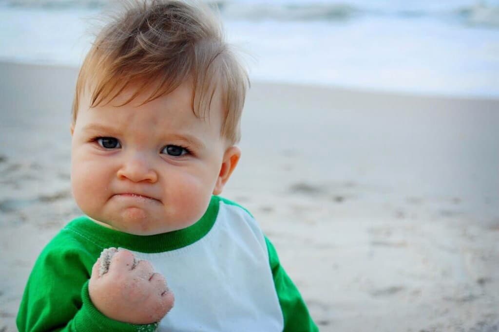Success Kid meme showing a toddler on a beach clenching a fist with a determined expression